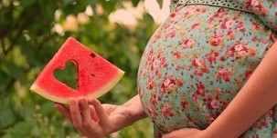 ฝานแตงโมอยู่ในมือของหญิงตั้งครรภ์